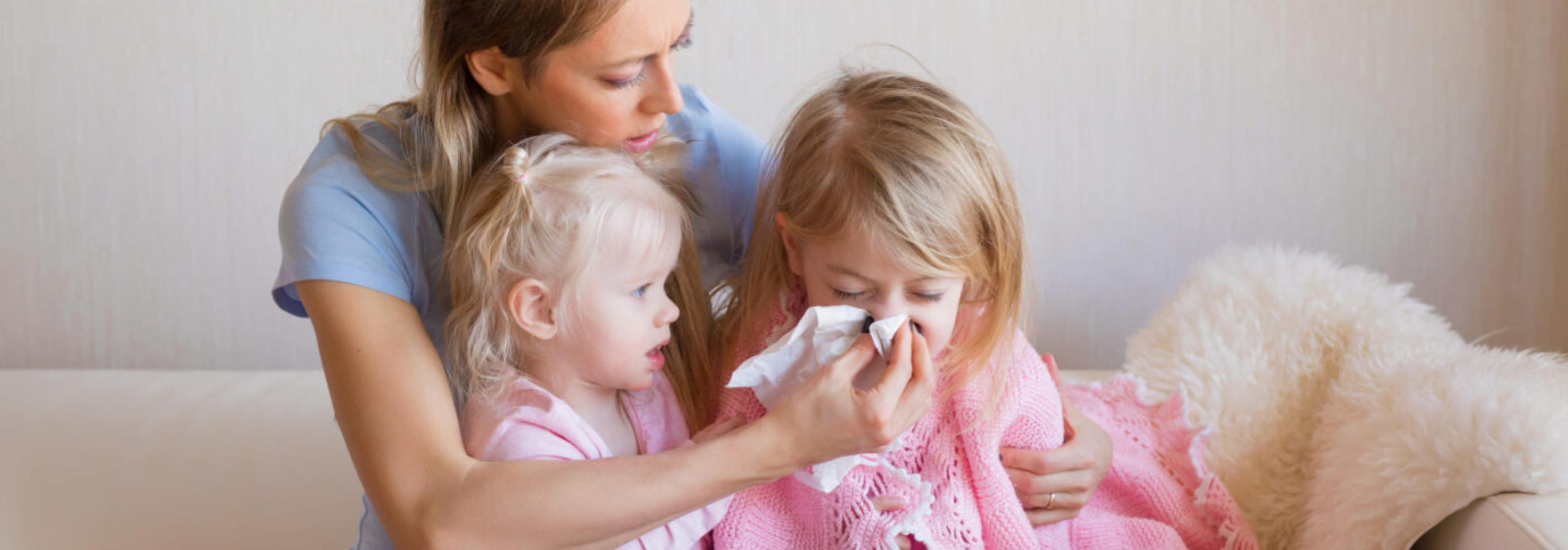 Mother comforting her two children, who appear to be unwell with coughs and colds.